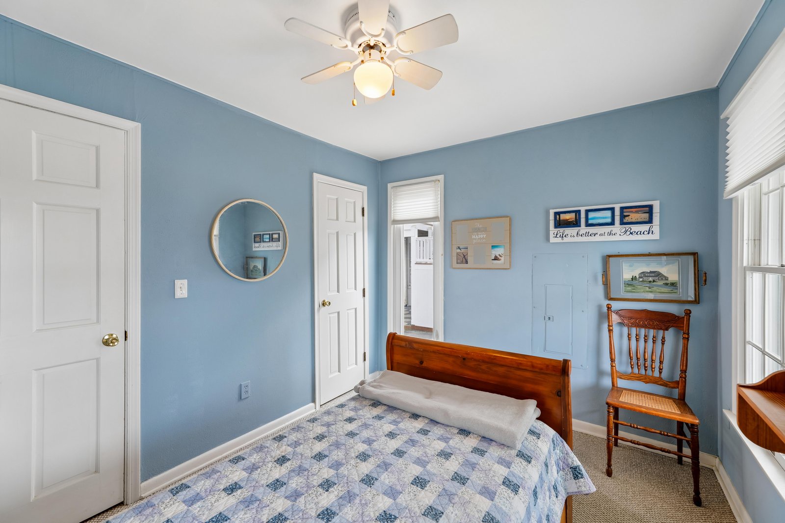 Your cozy coastal bedroom awaits—soft blue walls, a comfy bed, and gentle ceiling fan breezes make it easy to unwind after beach days.