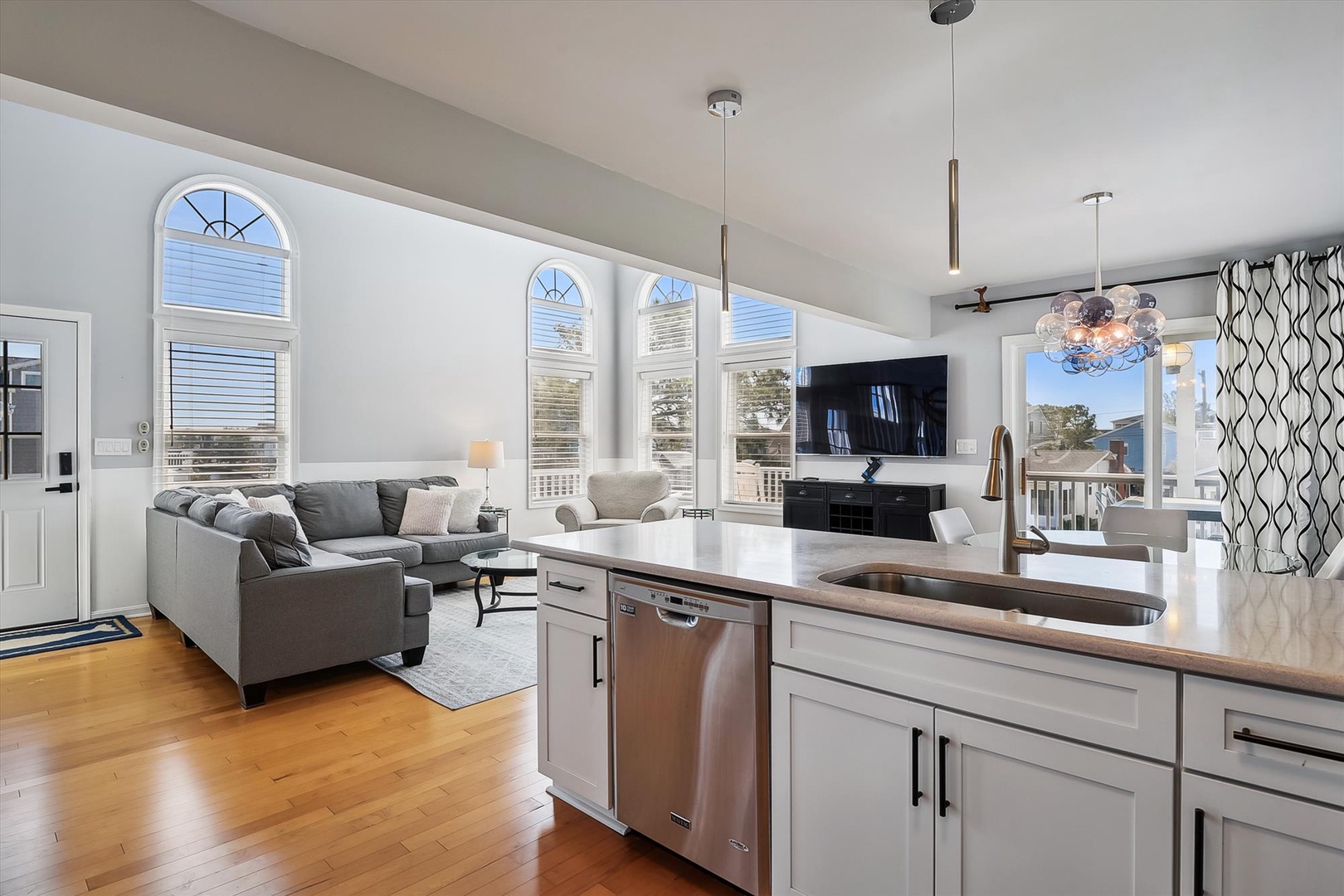 Sunlight pours through elegant arched windows into your open-concept living space, where a chef's kitchen flows seamlessly into a cozy lounge—perfect for entertaining or unwinding after exploring the area.