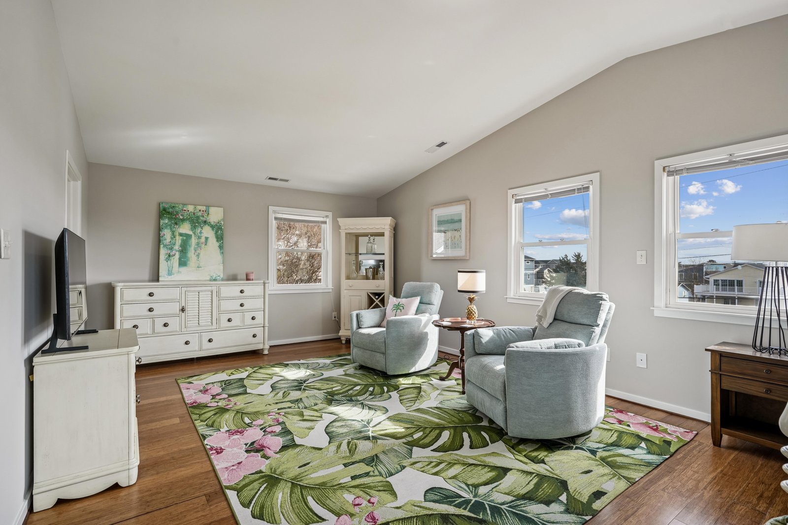 Settle into this bright living room where soft seating and abundant natural light create your perfect retreat. Large windows frame peaceful neighborhood views as you unwind in comfort.
