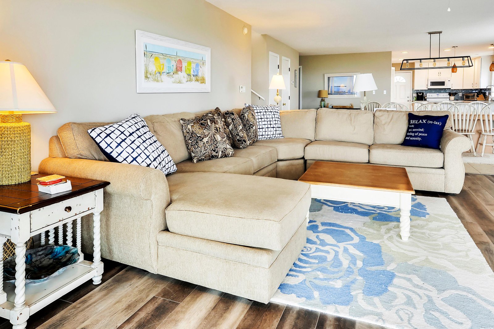 Sink into your spacious living room with plush sectional seating, coastal accents, and an open flow into the kitchen—perfect for relaxing after a day by the shore.