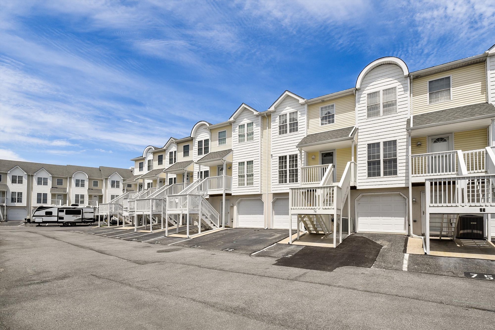 Attractive townhouse-style vacation rental complex with private garages and elevated entryways, set in a quiet residential area with ample parking for guests.