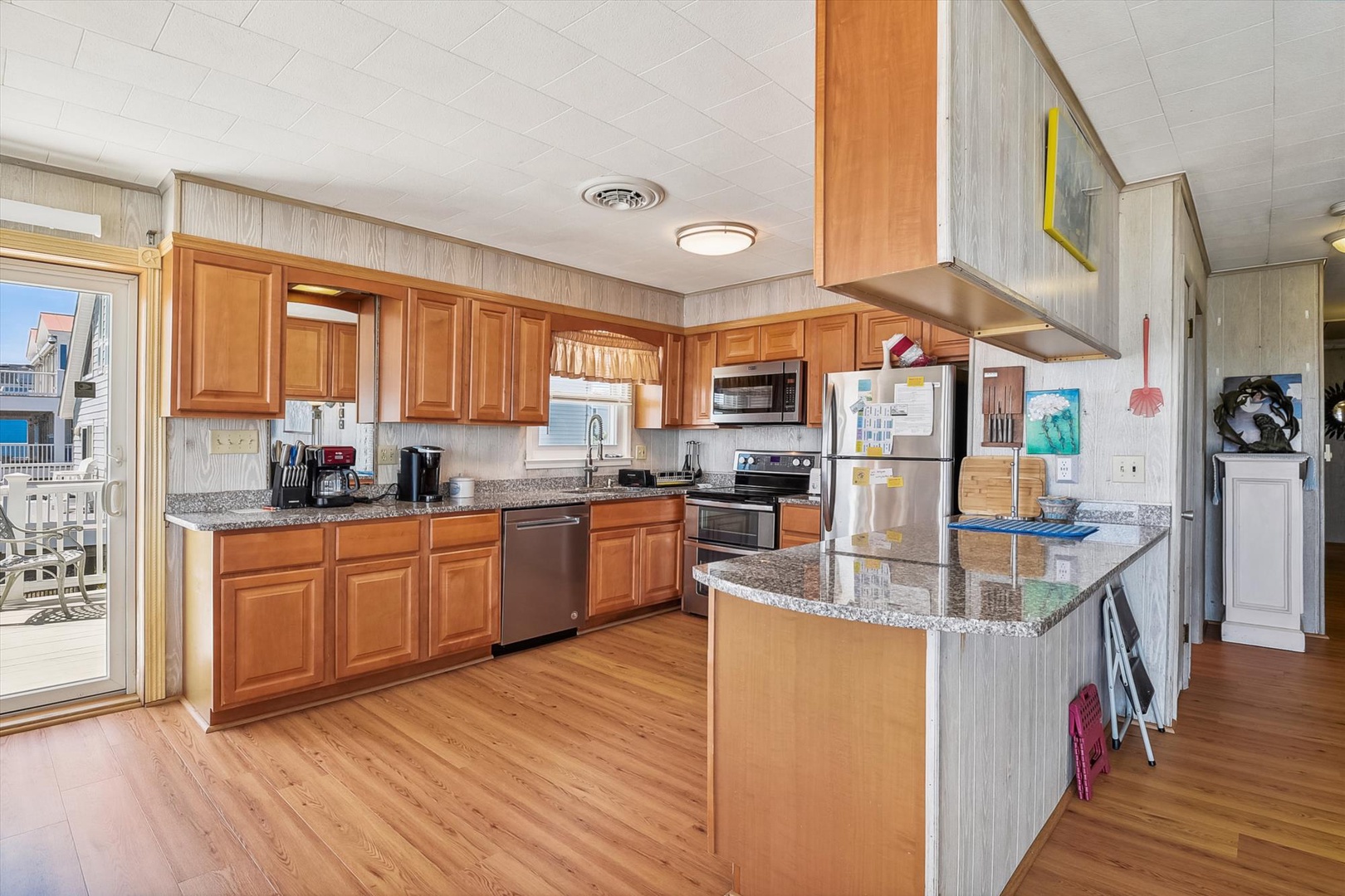 Your fully equipped kitchen with granite countertops and spacious island invites you to prepare home-cooked meals while enjoying natural light streaming through the windows overlooking nearby homes.