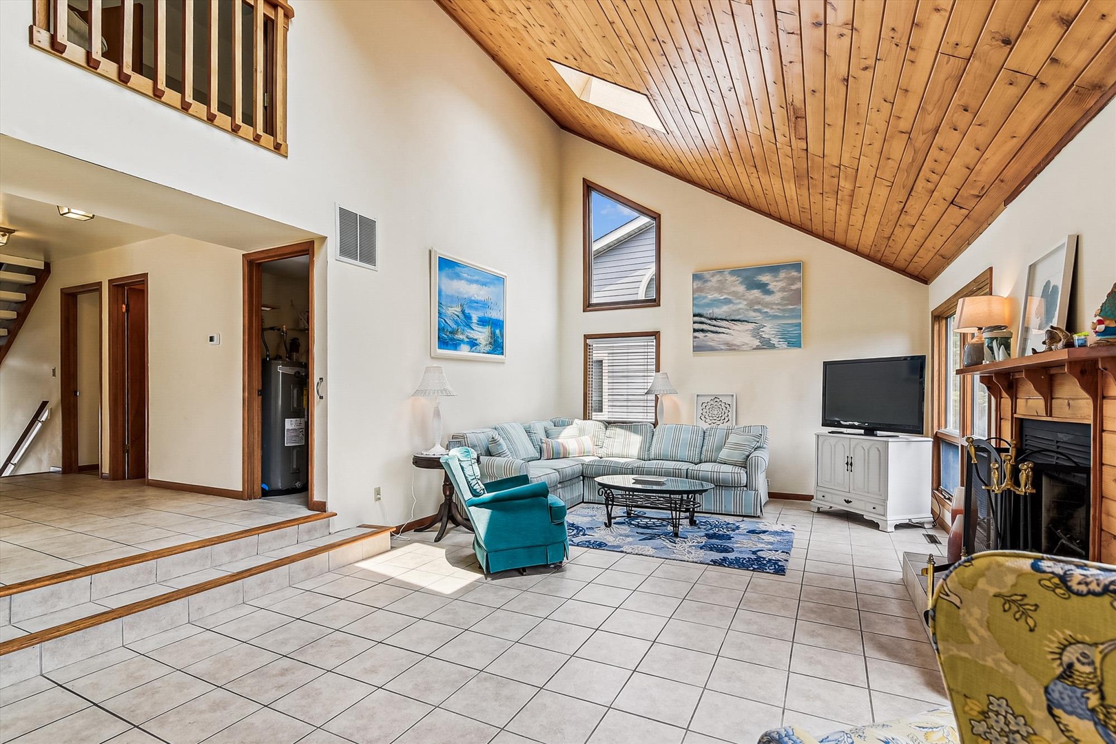 Unwind in your spacious living room with soaring vaulted ceilings and warm wood accents. Natural light floods through the skylight, while beach-inspired artwork sets a coastal mood for your getaway.