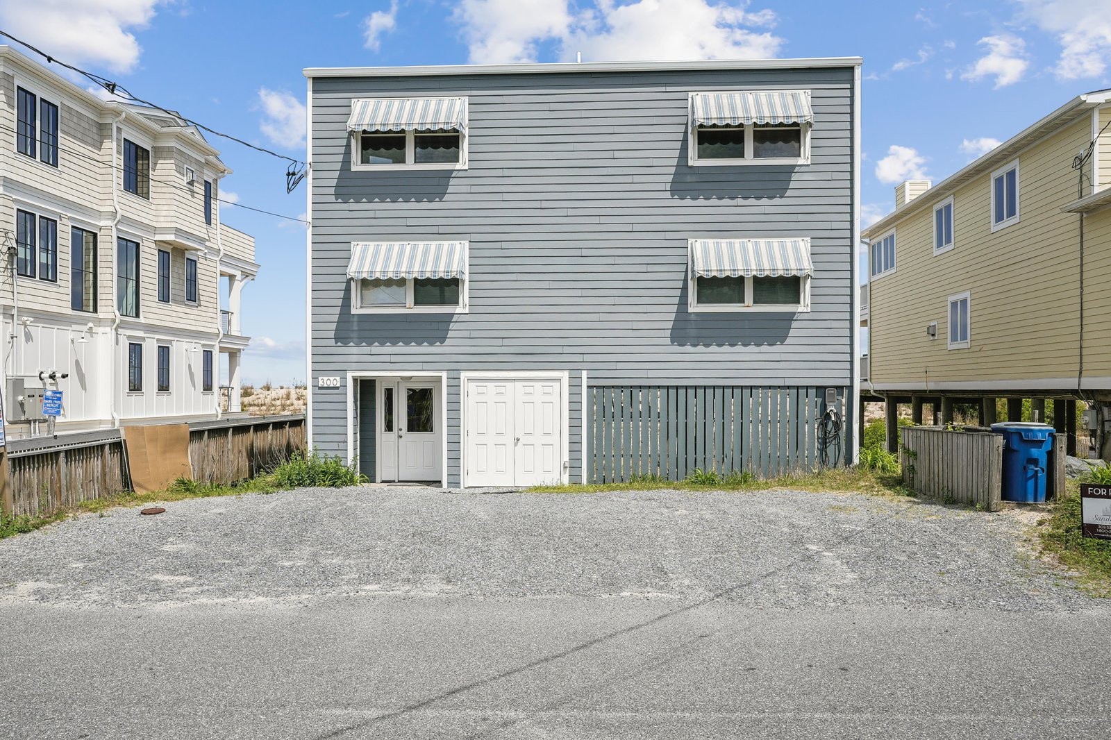 A coastal property with convenient parking and charming striped awnings, located in a quiet beach neighborhood close to the shore.