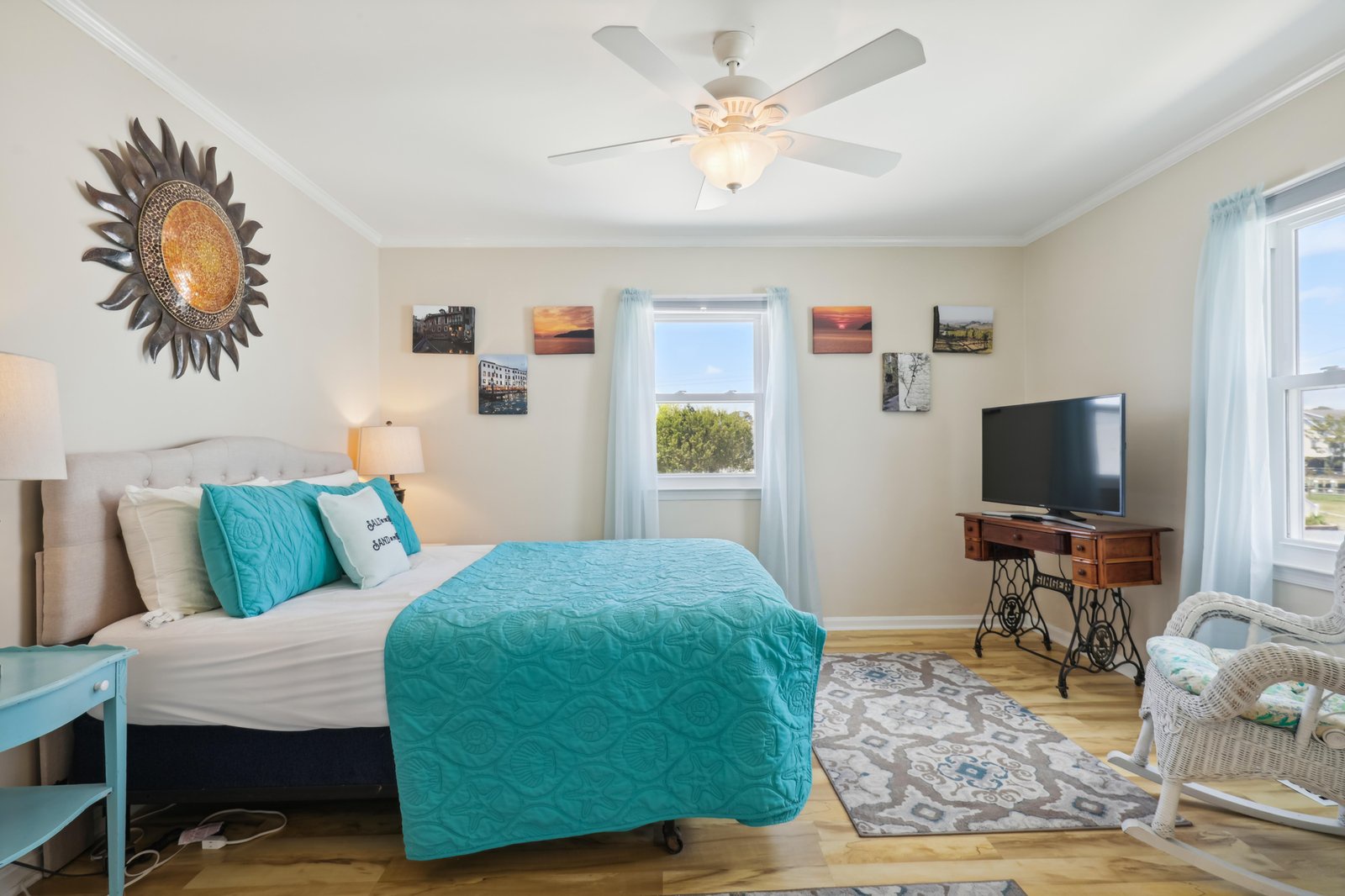 Your inviting bedroom features a plush bed with bright turquoise accents, warm hardwood floors, and gentle natural light from windows framing peaceful neighborhood views.
