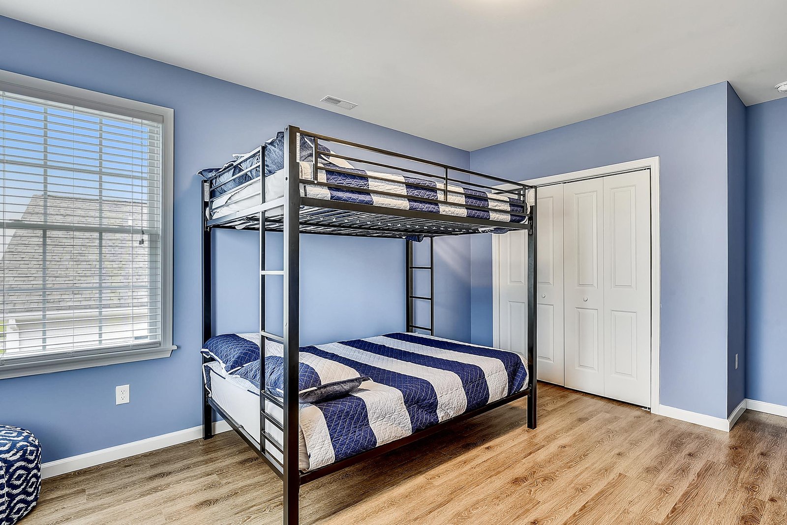 Your kids will love claiming their favorite bunk in this cheerful blue bedroom, where nautical-striped bedding and warm wood floors create a cozy retreat after a day of adventure.