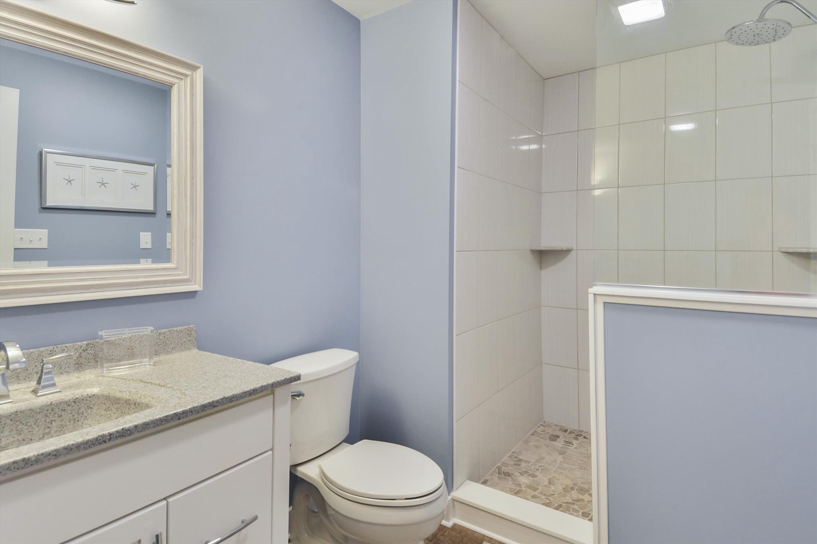 Your private bathroom features a bright, clean design with a spacious walk-in shower, modern vanity with granite countertop, and fresh towels waiting for your arrival.