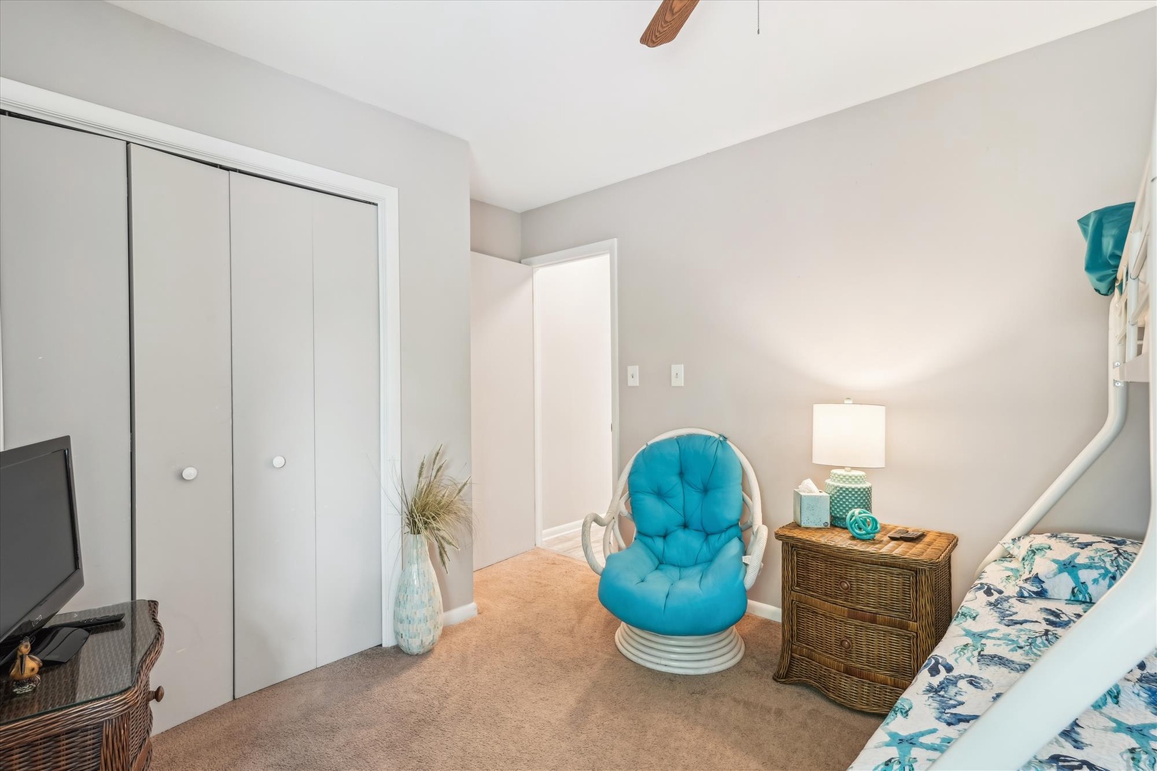 Relax in your serene bedroom featuring a cozy turquoise accent chair and natural wicker furniture that create the perfect coastal retreat.