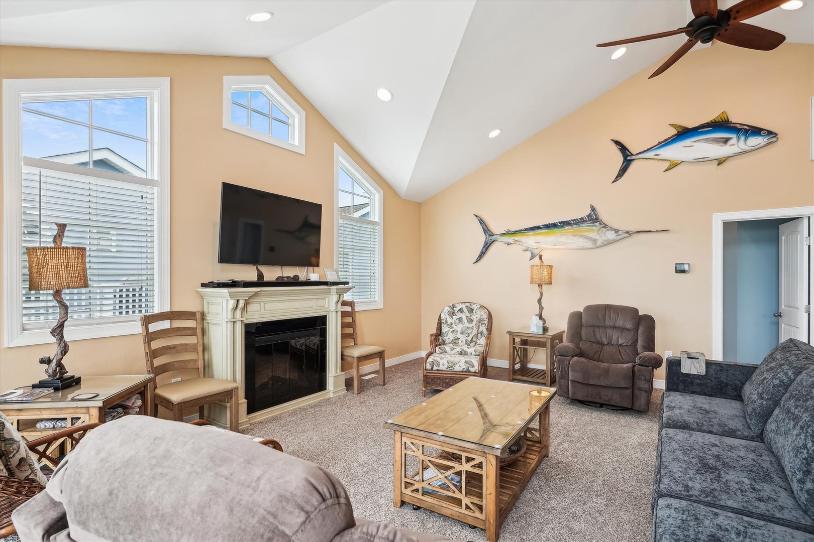 Sink into plush seating beneath soaring vaulted ceilings and coastal-inspired fish decor. Your cozy living room features a fireplace for chilly evenings, a flat-screen TV, and natural light from large windows.