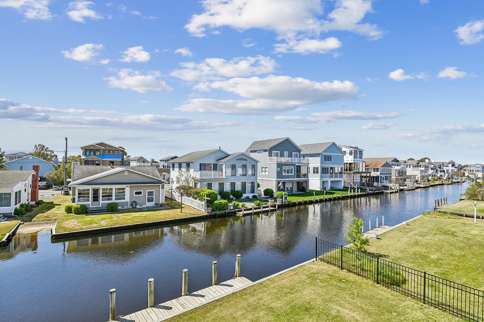 Waterfront residential community featuring canal access with private docks and manicured lawns under a partly cloudy sky.