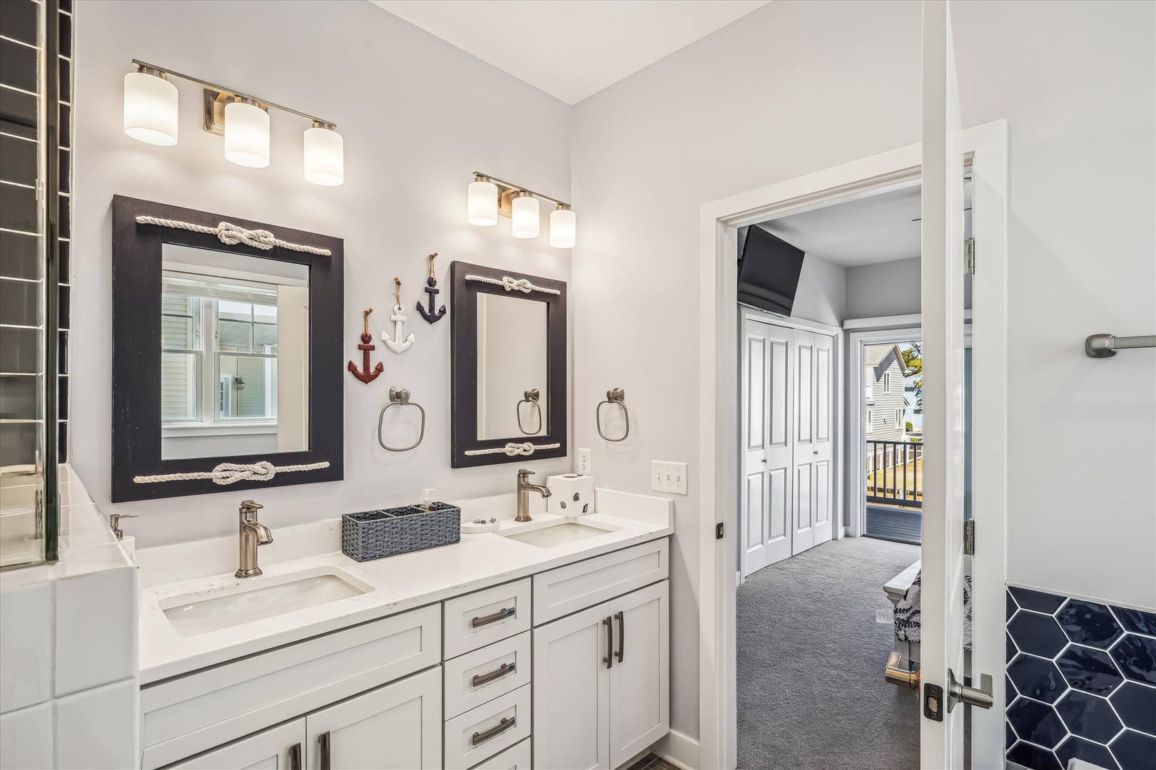 Your private bathroom features dual vanities with nautical-themed mirrors, bright lighting, and thoughtful coastal touches that bring vacation vibes to your morning routine.