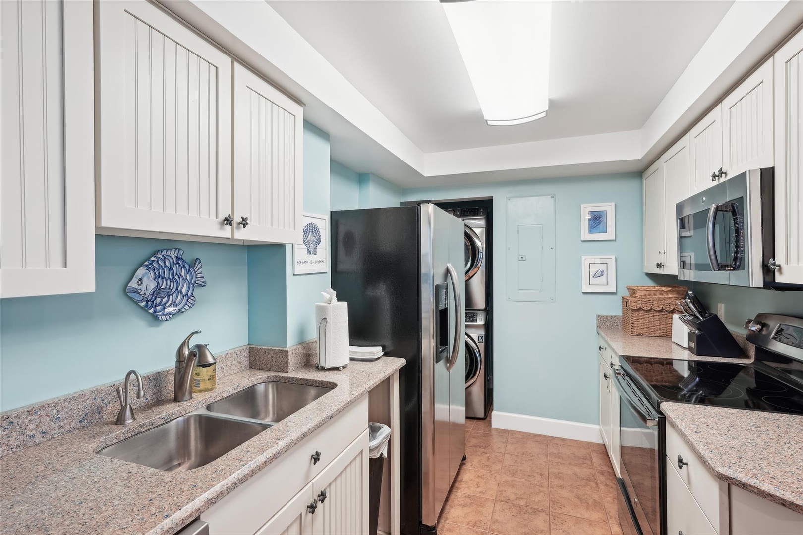 Your fully-equipped kitchen features granite countertops, stainless appliances, and calming coastal blue walls that make cooking feel like a beachside retreat.