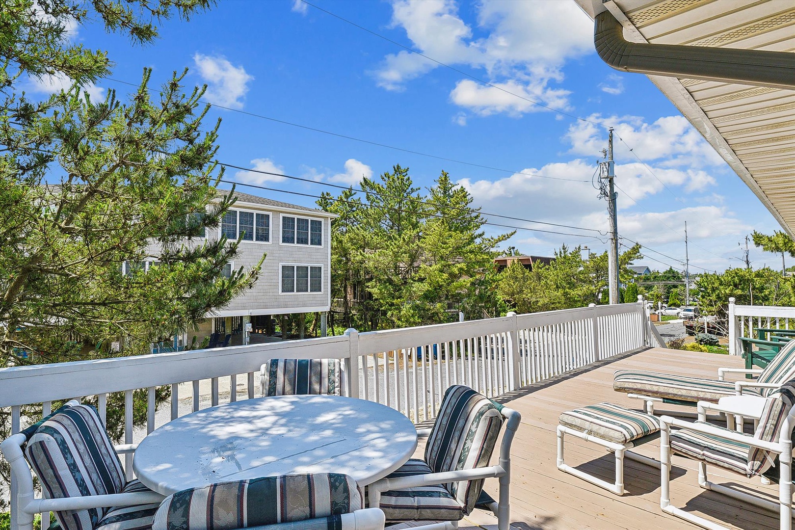 A private balcony captures the surrounding coastal neighborhood, with shaded trees and nearby properties visible in the distance—an ideal spot for taking in the area's quiet ambiance.