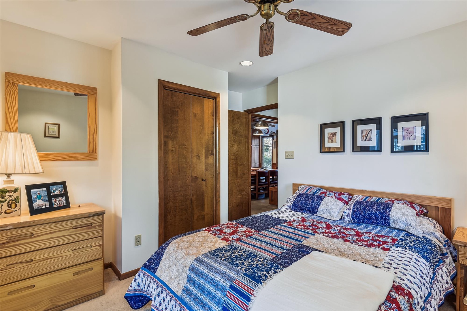 Step into your inviting bedroom where a cozy quilt-dressed bed awaits beneath a gentle ceiling fan, with warm lighting and charming décor welcoming you to unwind.