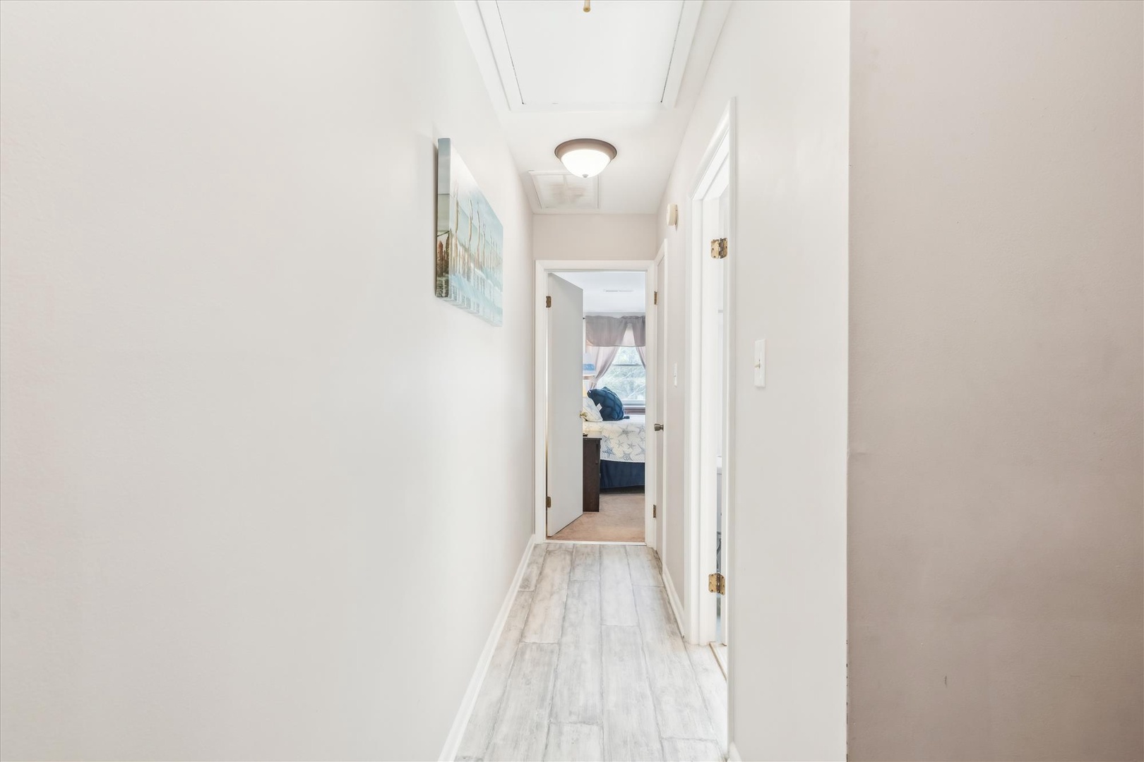 A bright, airy hallway with light wood-style flooring leads to your cozy bedroom, where sunshine and comfort await your arrival.