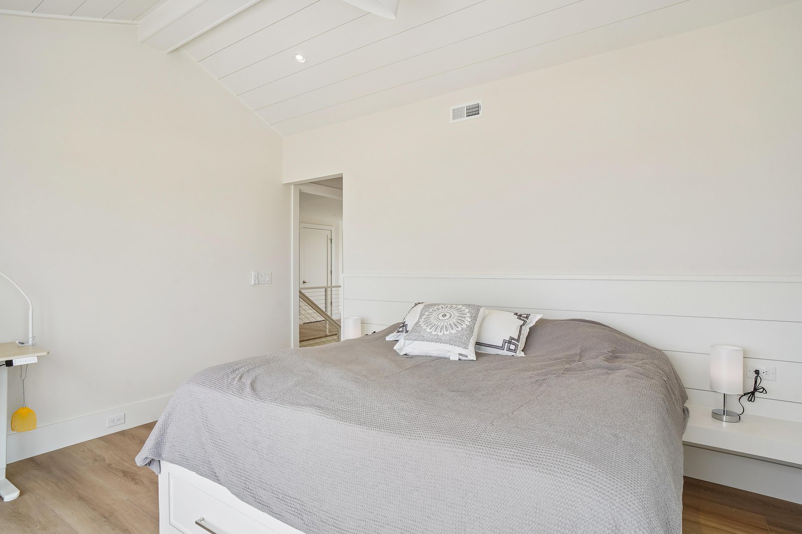 Step into your serene sleeping space with crisp white shiplap walls and vaulted ceilings that create an airy, peaceful retreat for restful nights.