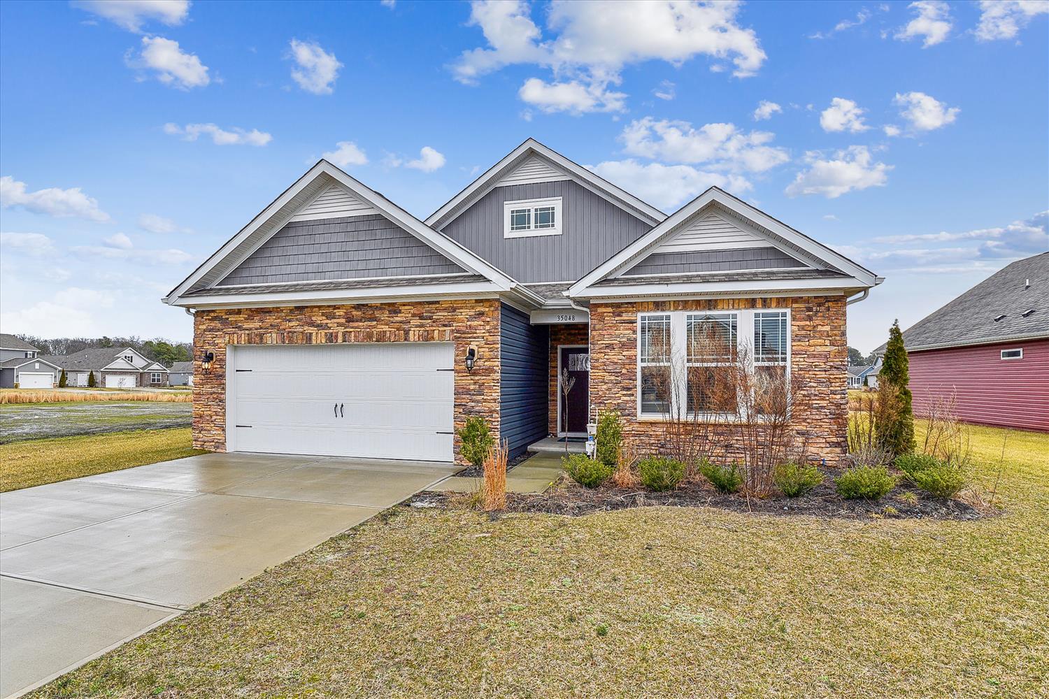 A charming single-story home with brick and siding exterior, featuring landscaped front yard and two-car garage in a quiet residential neighborhood.