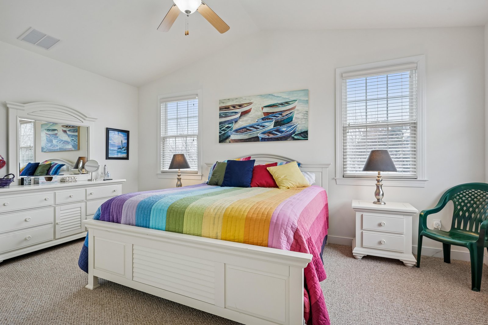 Relax in your bright, coastal-themed bedroom featuring a colorful quilt, beachy artwork, and nautical charm—perfect for restful mornings after sunny beach days.