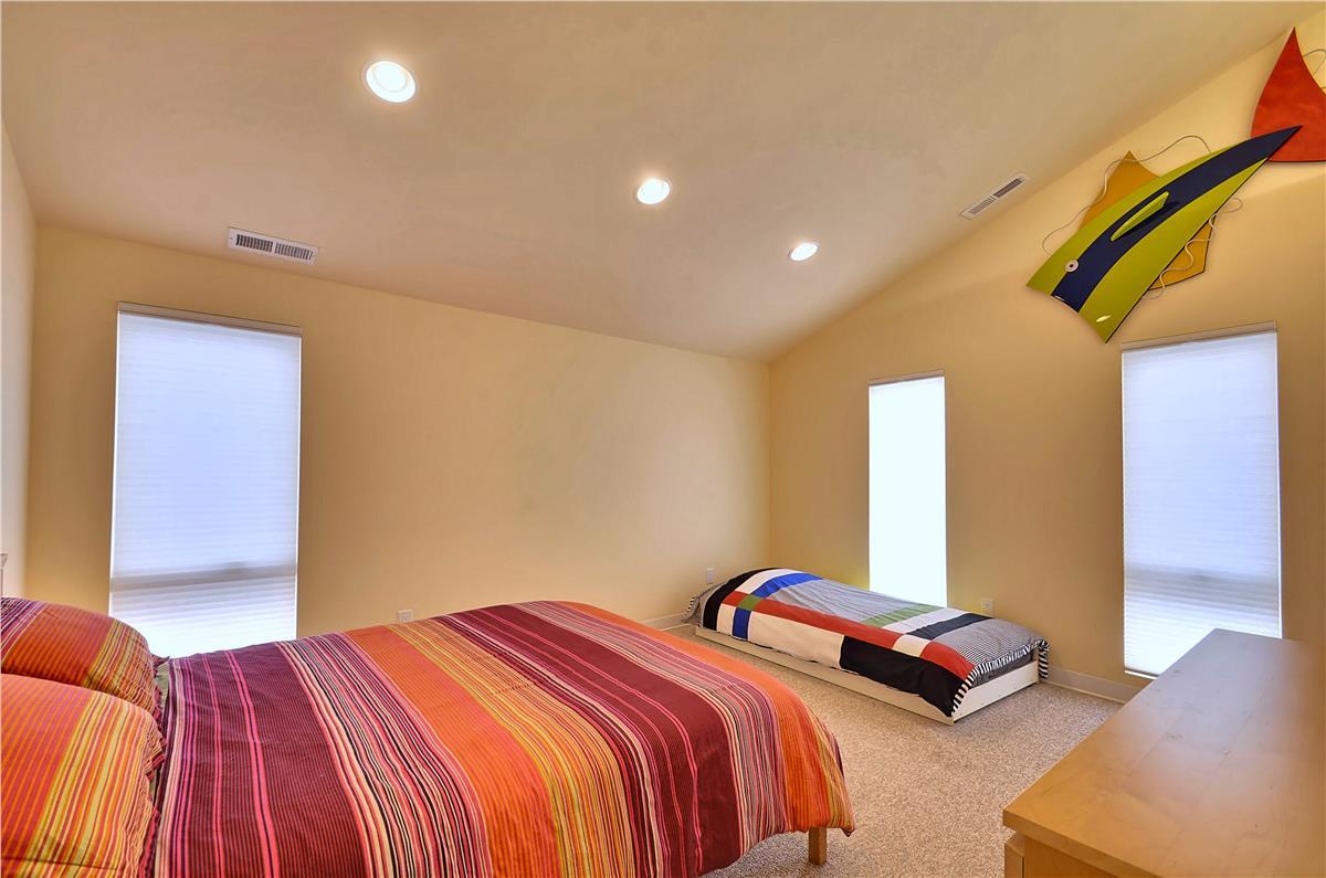 Your bright, cheerful bedroom offers a playful pop of color and plenty of space for restful nights beneath warm recessed lighting.