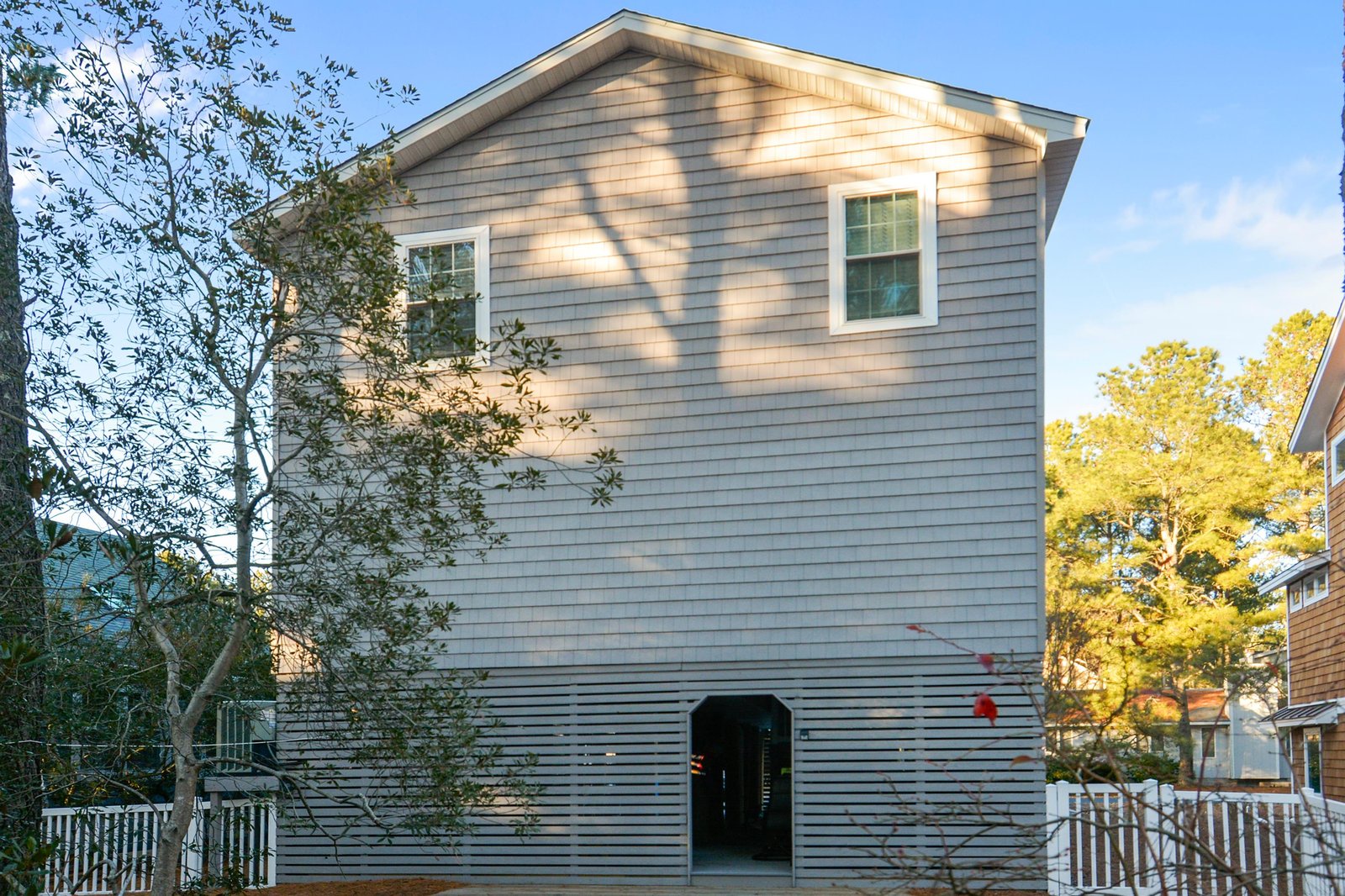 The property exterior, with natural wood siding and surrounded by trees, is located in a quiet residential neighborhood.