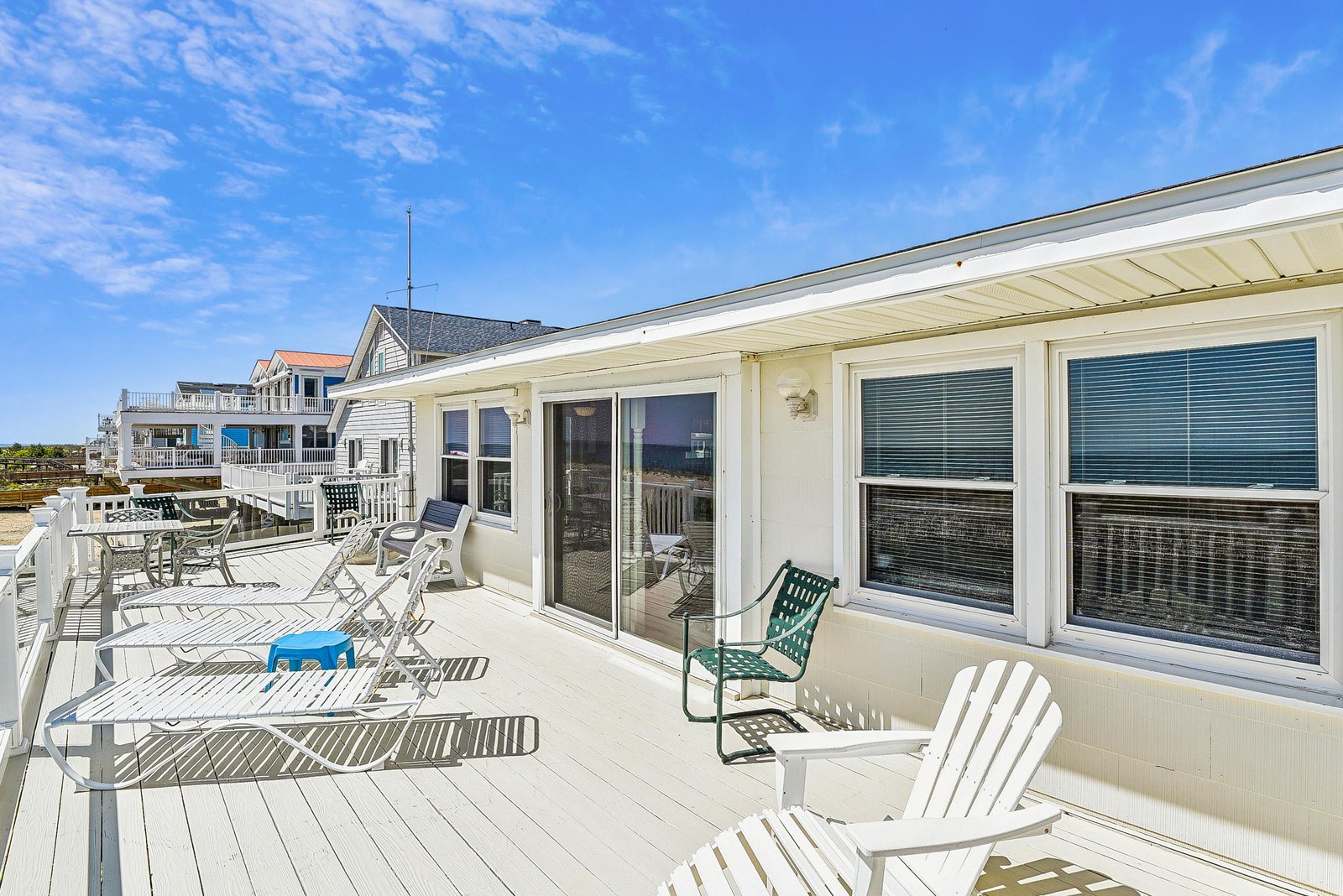 This beachside property features a spacious rooftop deck with nearby shore access and neighboring coastal homes.