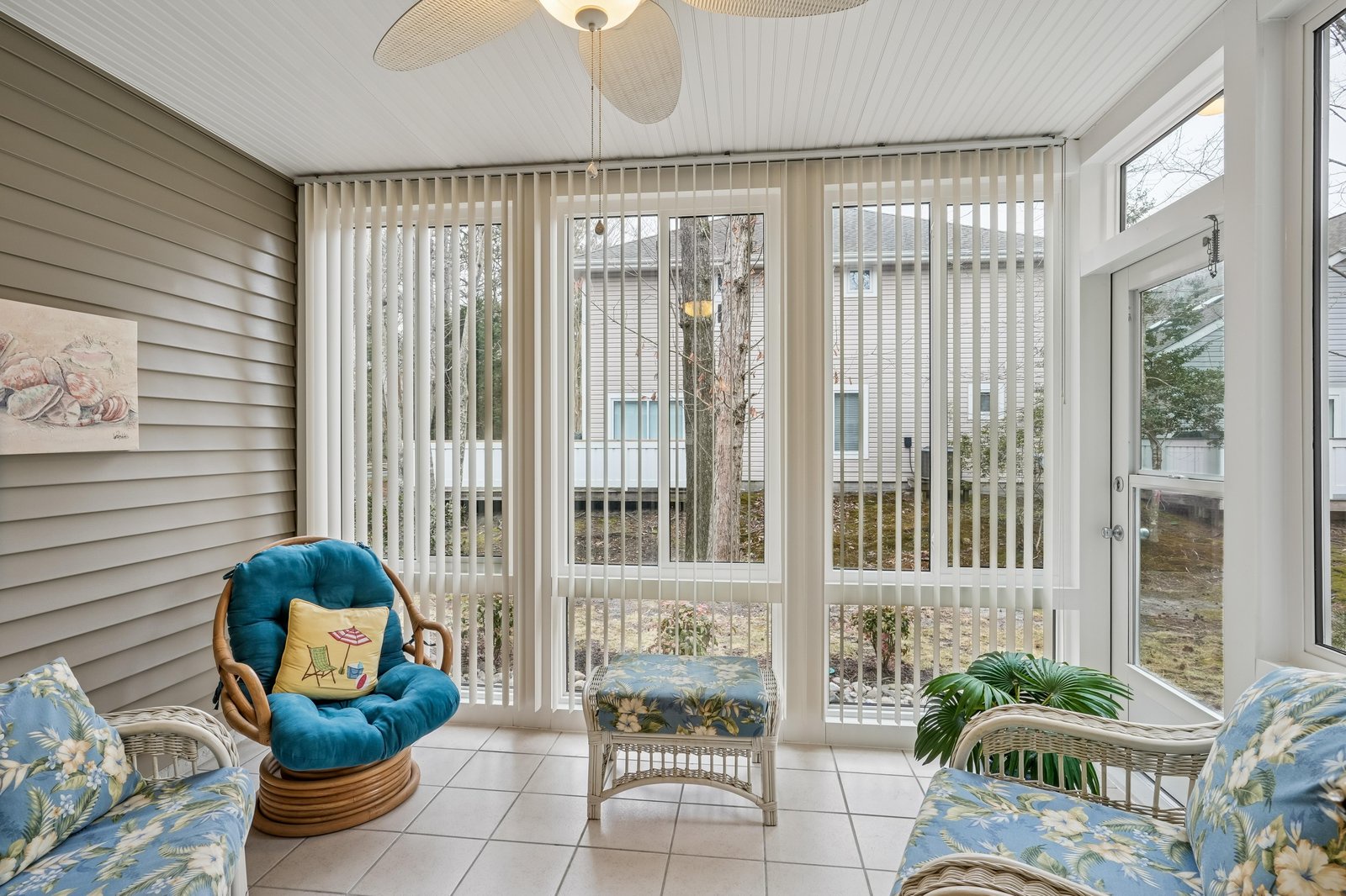 Unwind in your bright sunroom, where coastal-style seating and a gentle ceiling fan create the perfect retreat for morning coffee or reading in natural light.