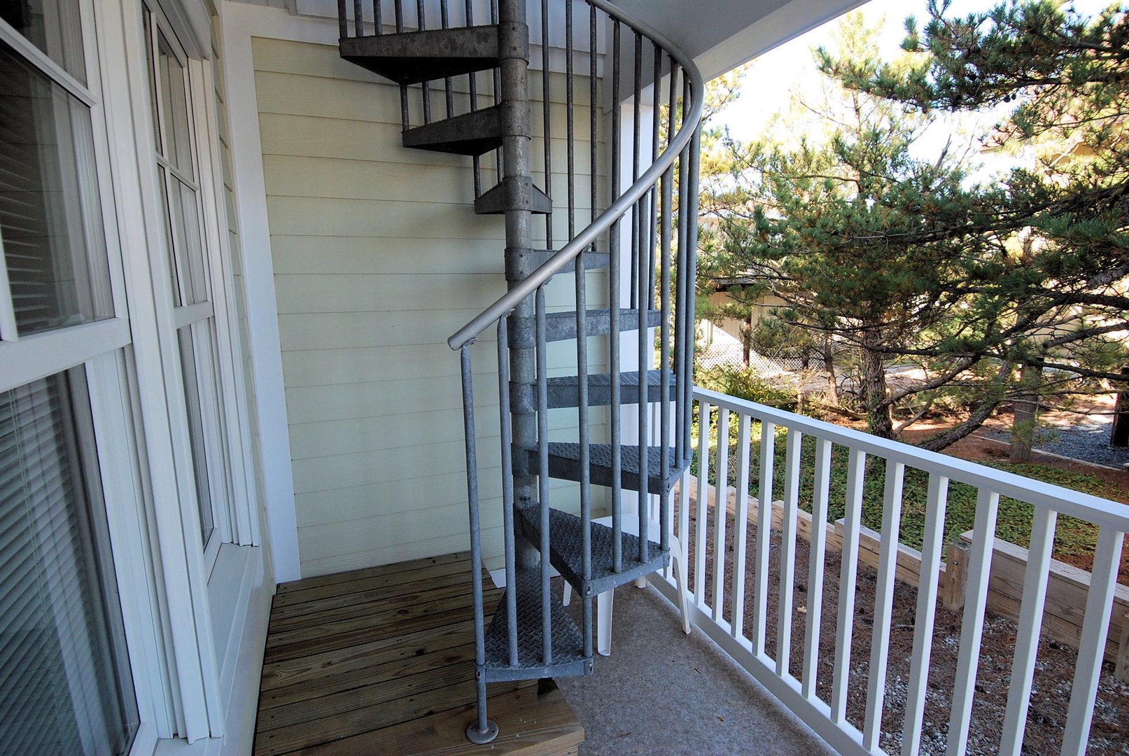 A charming balcony with spiral stairs provides outdoor space and tree-lined views for quiet moments.