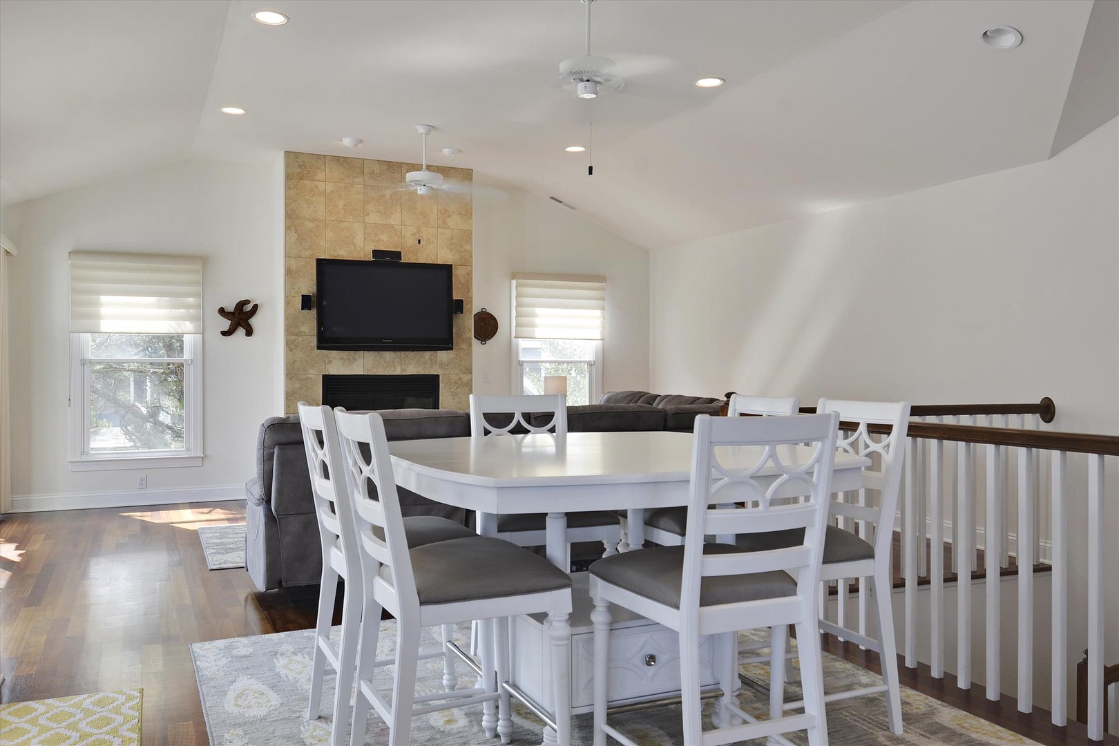 Step into your spacious open-concept living area, where natural light spills through large windows onto hardwood floors. Gather around the dining table after a beach day or relax by the fireplace beneath vaulted ceilings—your perfect home away from home.