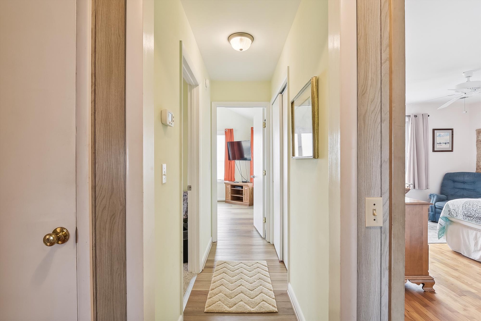 A welcoming hallway connects your private spaces with natural light and thoughtful design, featuring warm wood tones, mirrored accents, and a soft chevron runner underfoot.