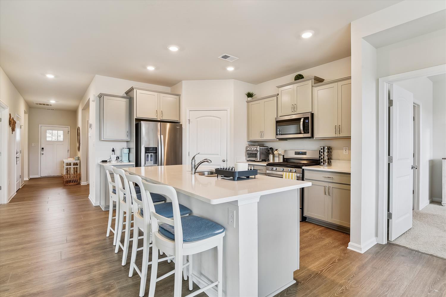 Gather around this bright, open kitchen where modern appliances meet coastal charm. Enjoy meal prep at the spacious island, perfect for quick bites or hosting friends in style.
