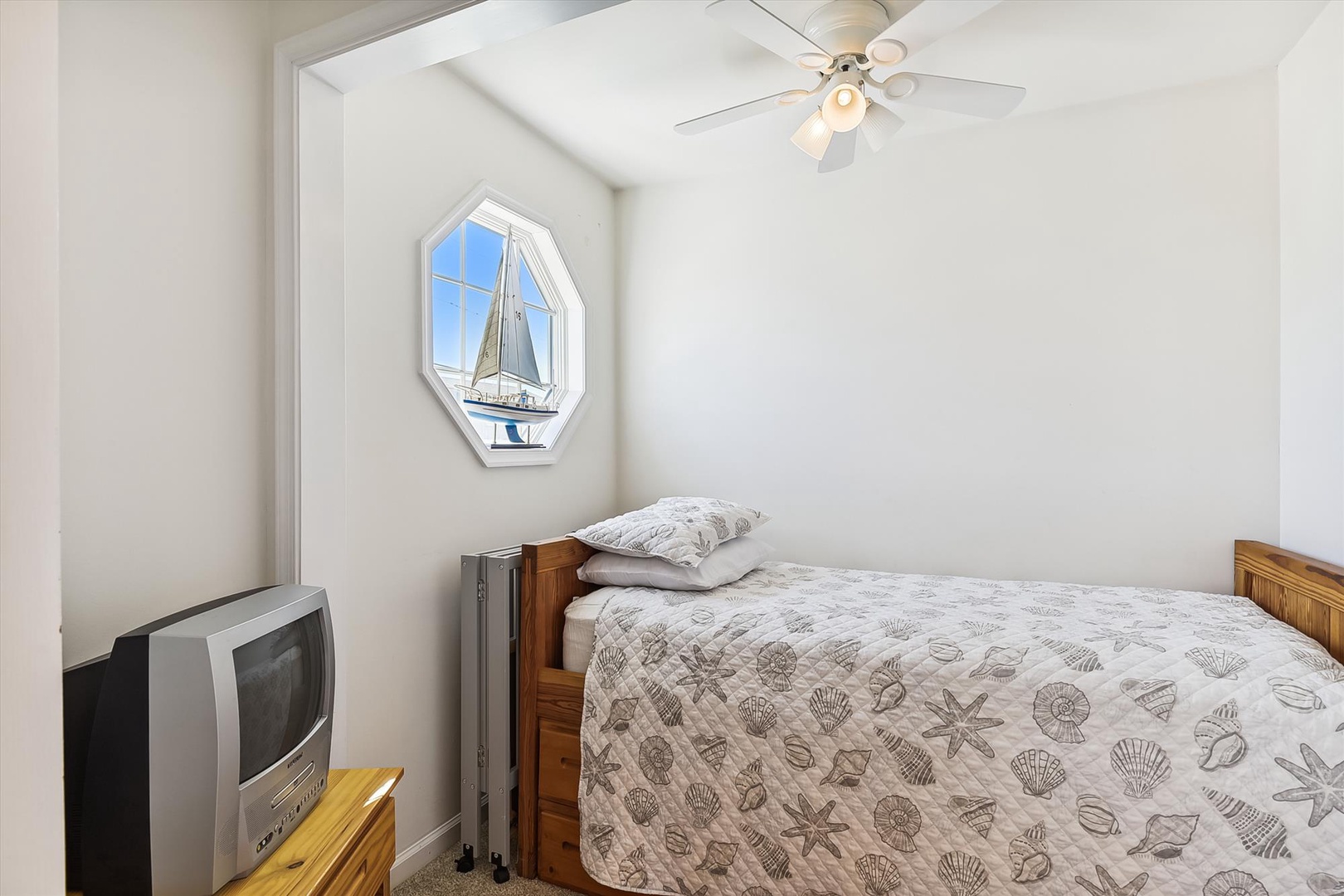 Drift off in this peaceful coastal bedroom with crisp linens, nautical art, and a gentle ceiling fan overhead keeping you comfortable all night long.