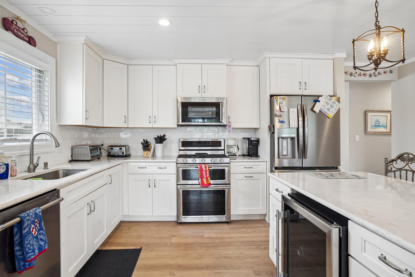 Step into your well-equipped kitchen, where bright white cabinetry and modern stainless appliances create a welcoming space for preparing meals and gathering with loved ones.