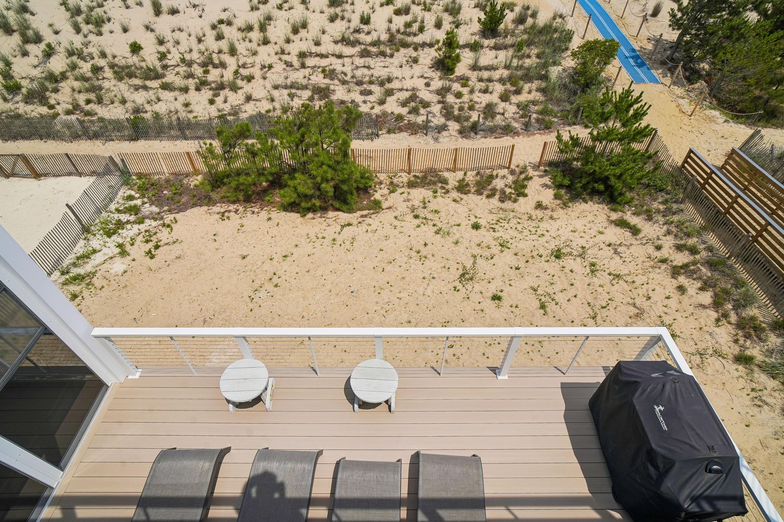 Aerial view of the property's deck overlooking natural coastal dunes and vegetation, offering a peaceful beachside setting.