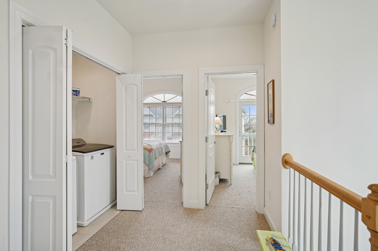Step into your bright upstairs hallway where thoughtful design connects peaceful bedrooms and a convenient laundry area.