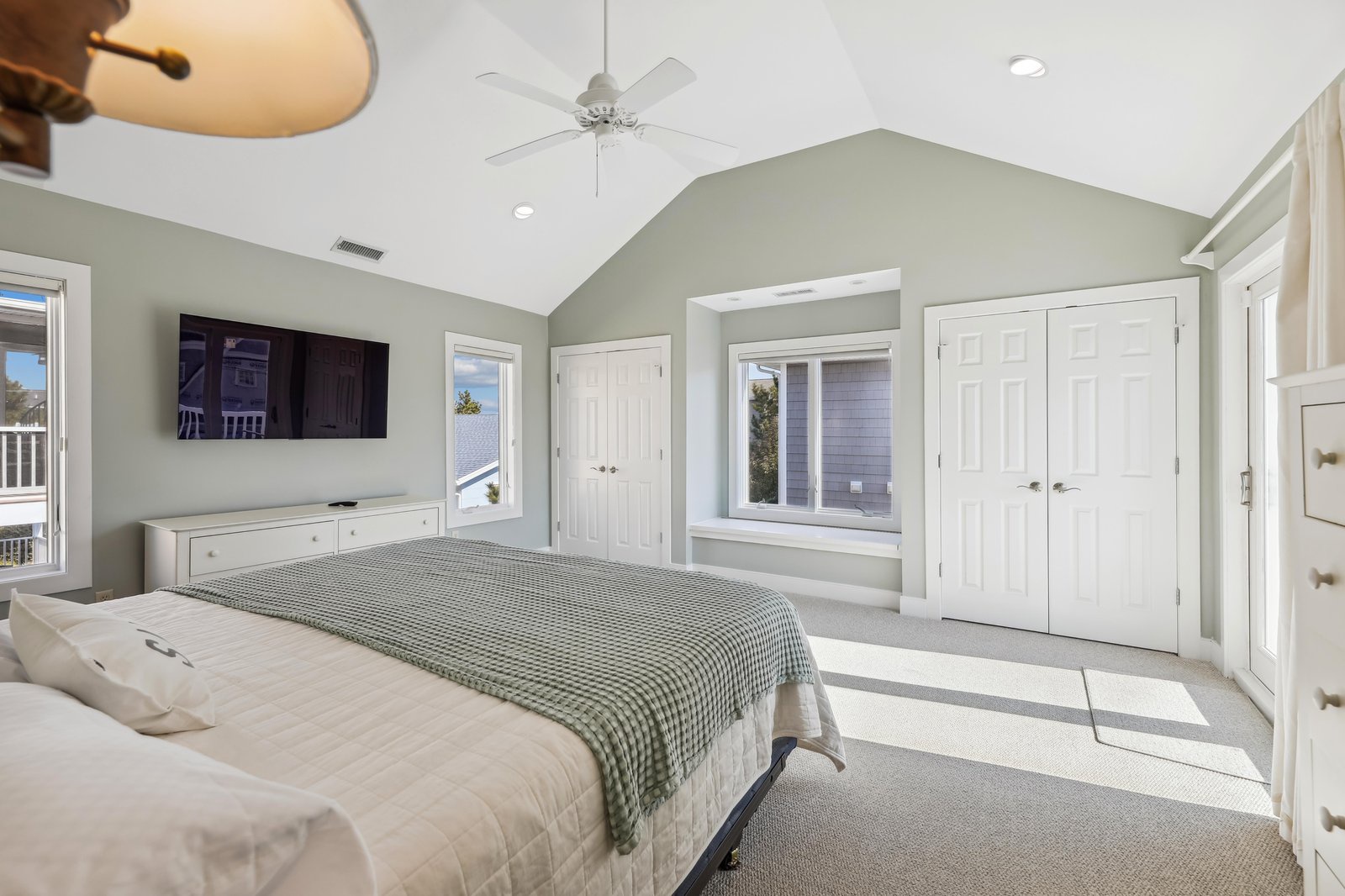 Settle into your serene primary bedroom with vaulted ceilings, gentle natural light, and crisp sage-green walls—a peaceful retreat designed for restful nights and easy mornings.