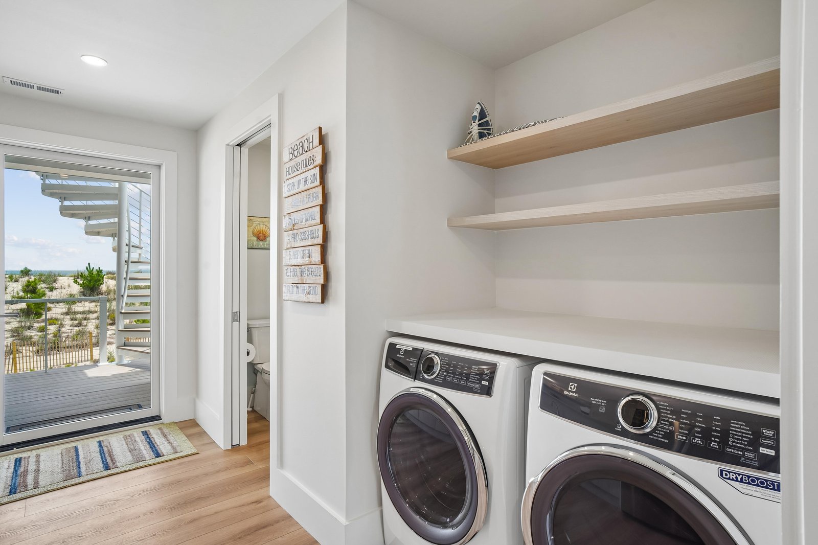 Your laundry routine just got easier with this bright, convenient space featuring a full-size washer and dryer, open shelving for supplies, and a door leading straight outside to the patio.