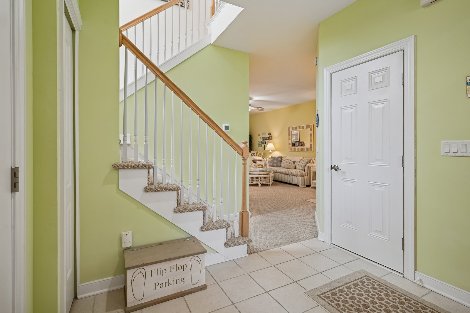 Step into your welcoming entryway with cheerful green walls and polished staircase leading to comfortable living spaces above.