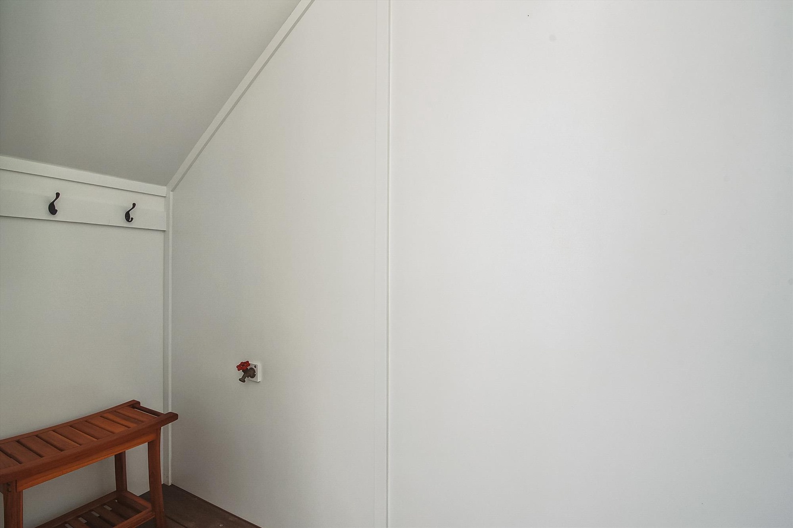 A clean, minimalist entryway with coat hooks and a wooden bench provides a simple, organized space for your arrival.