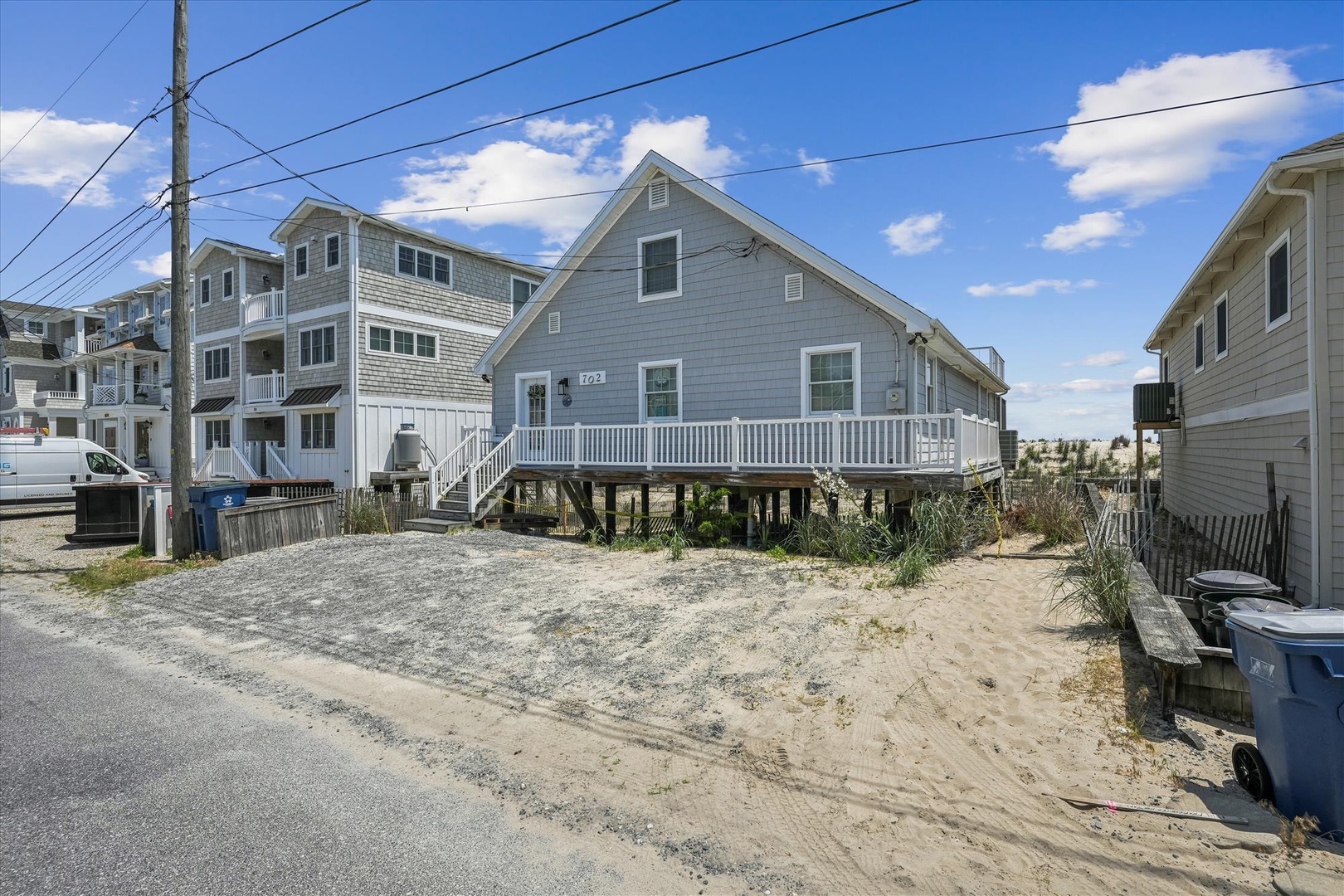 Beachfront property situated on a sandy street in a coastal neighborhood, surrounded by similar vacation homes and just steps from the ocean.