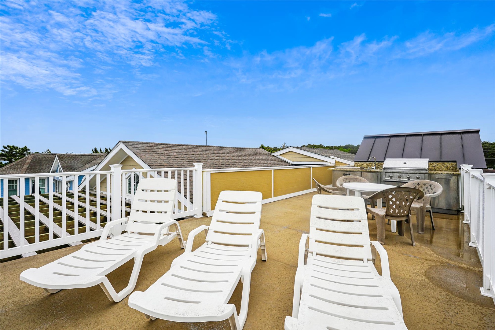 A private rooftop deck features lounge chairs, outdoor dining space, and wide views of the colorful neighborhood and surrounding landscape—perfect for morning coffee or sunset relaxation.