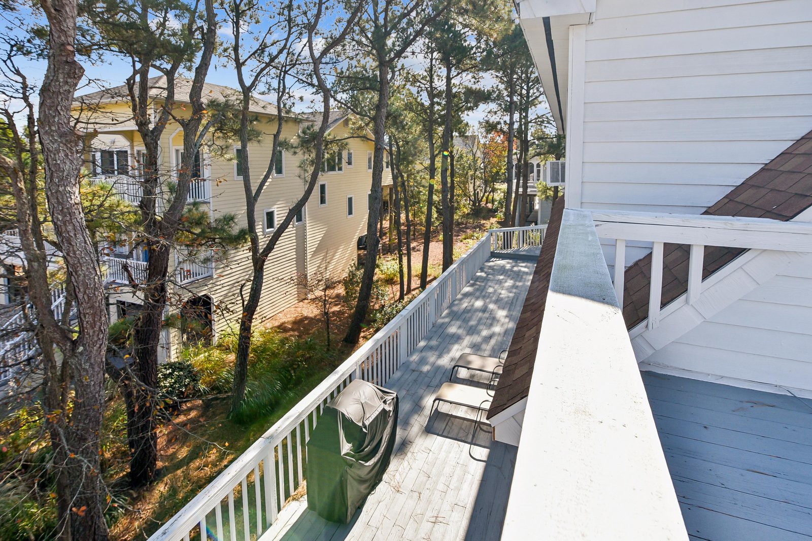Property nestled in a peaceful wooded neighborhood, surrounded by mature trees and coastal vegetation. The private balcony offers fresh air and quiet surroundings with neighboring homes nearby.