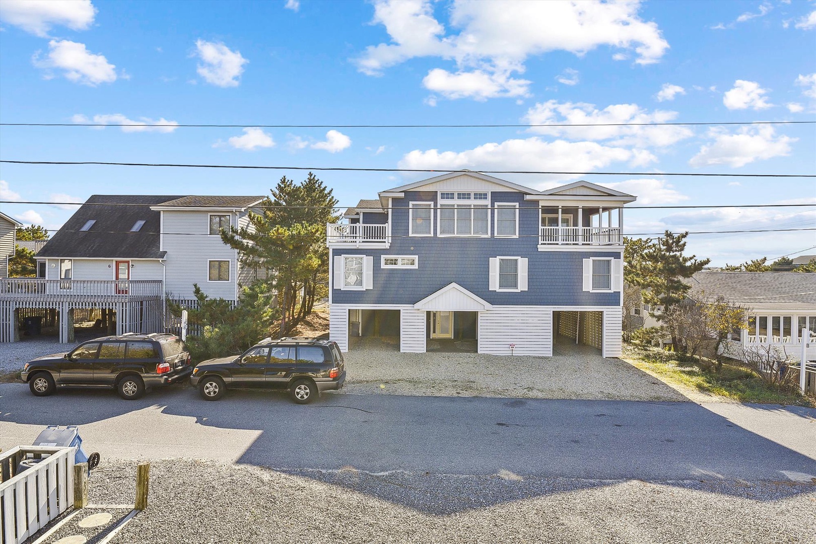 Coastal beach property with multiple levels, balconies, and ample parking nestled among neighboring beach houses.