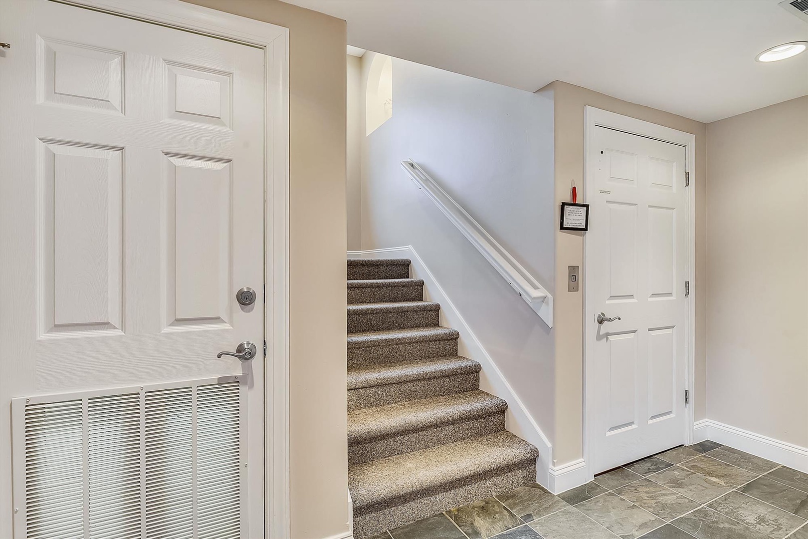 Clean, neutral-toned entryway with carpeted stairs leading to your private upstairs living space, offering easy access throughout your rental home.