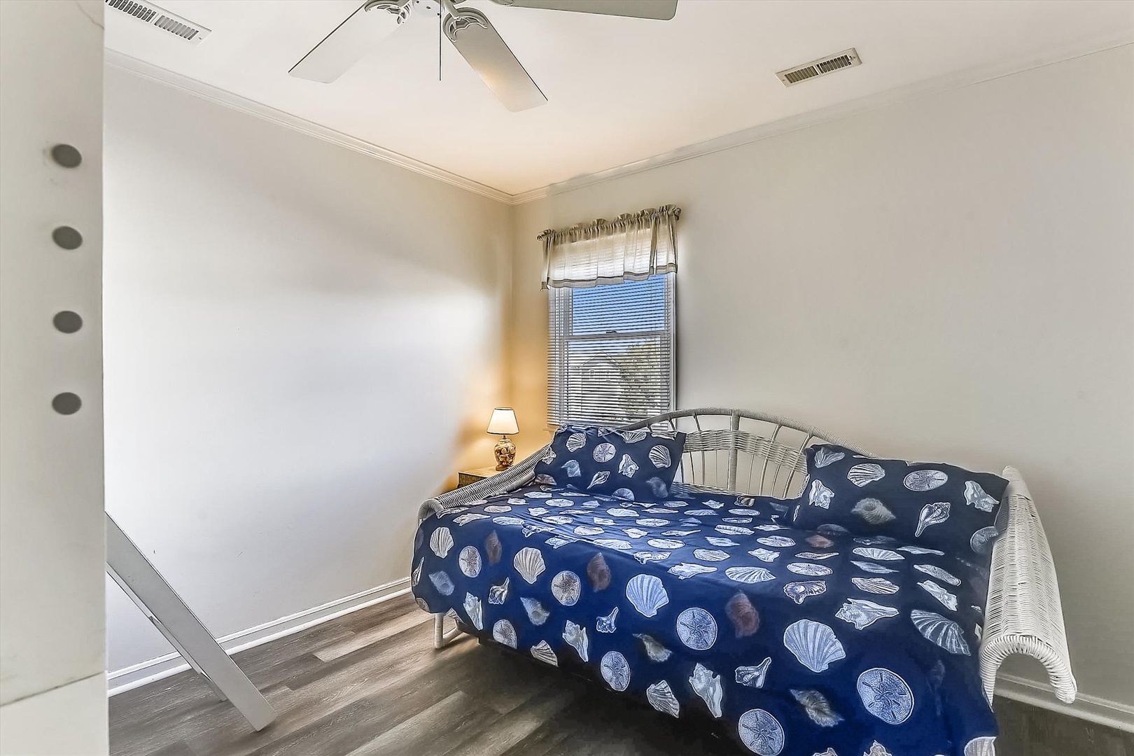 Drift off in your peaceful bedroom with coastal charm—a nautical daybed under soft ceiling fan breezes and natural light streaming through the window.