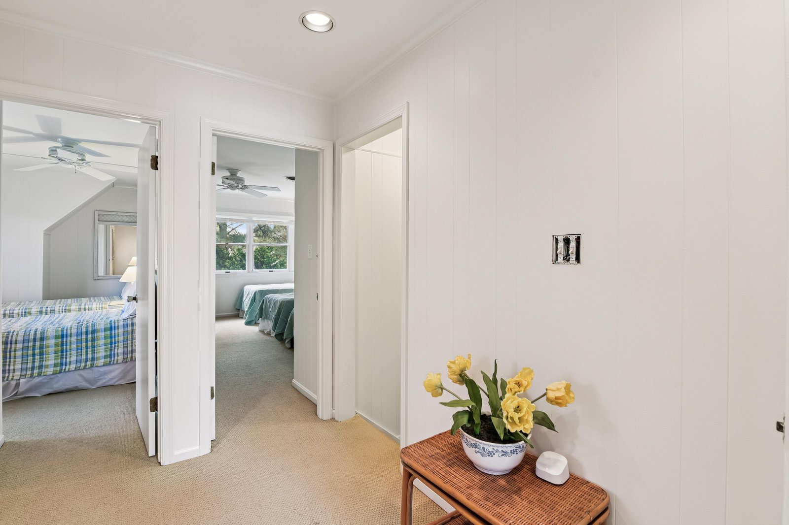 A bright, welcoming hallway connects your peaceful bedrooms, with soft carpeting underfoot and cheerful flowers adding a homey touch to this private retreat.