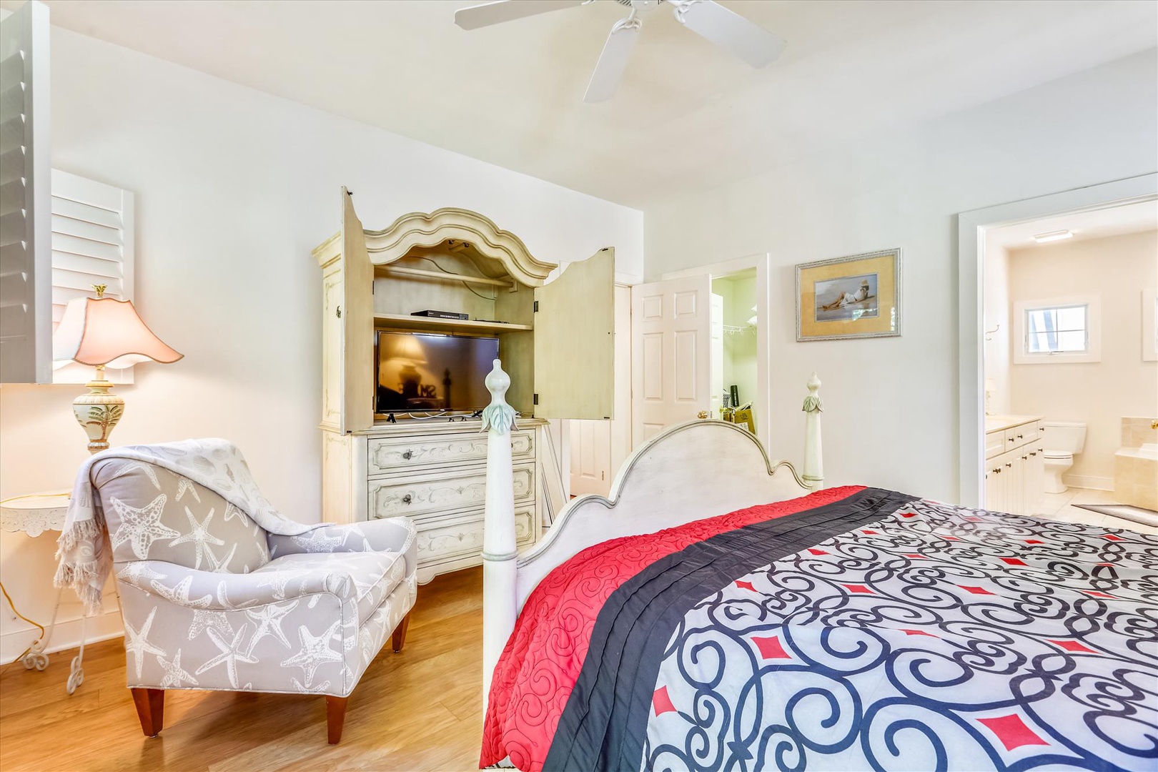 Unwind in your serene bedroom featuring coastal charm, a plush bed with vibrant linens, and a cozy armchair perfect for relaxing. Your ensuite bathroom awaits just steps away.