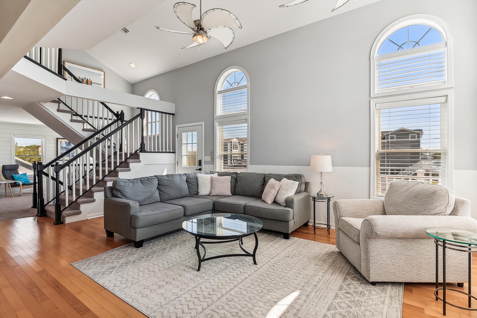 Sink into plush seating beneath soaring ceilings and elegant arched windows that fill your retreat with natural light and breezy coastal charm.