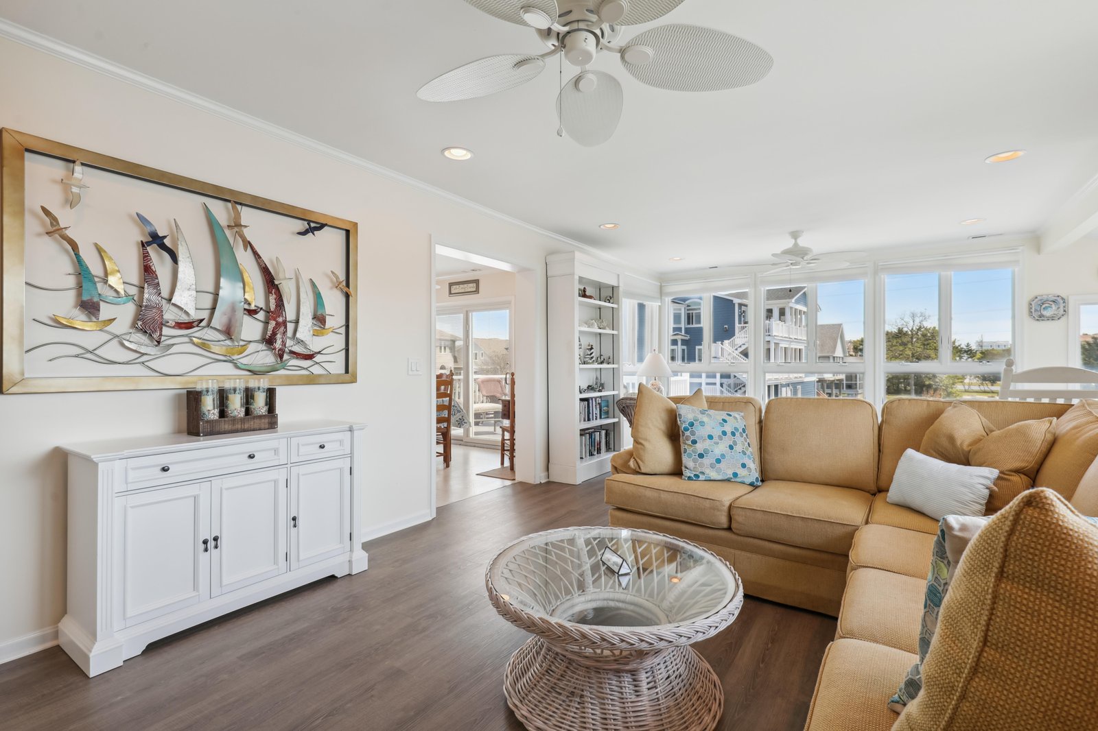 Relax into coastal comfort in your airy living room, where ceiling fans keep things breezy and sunlight streams through oversized windows overlooking the neighborhood.