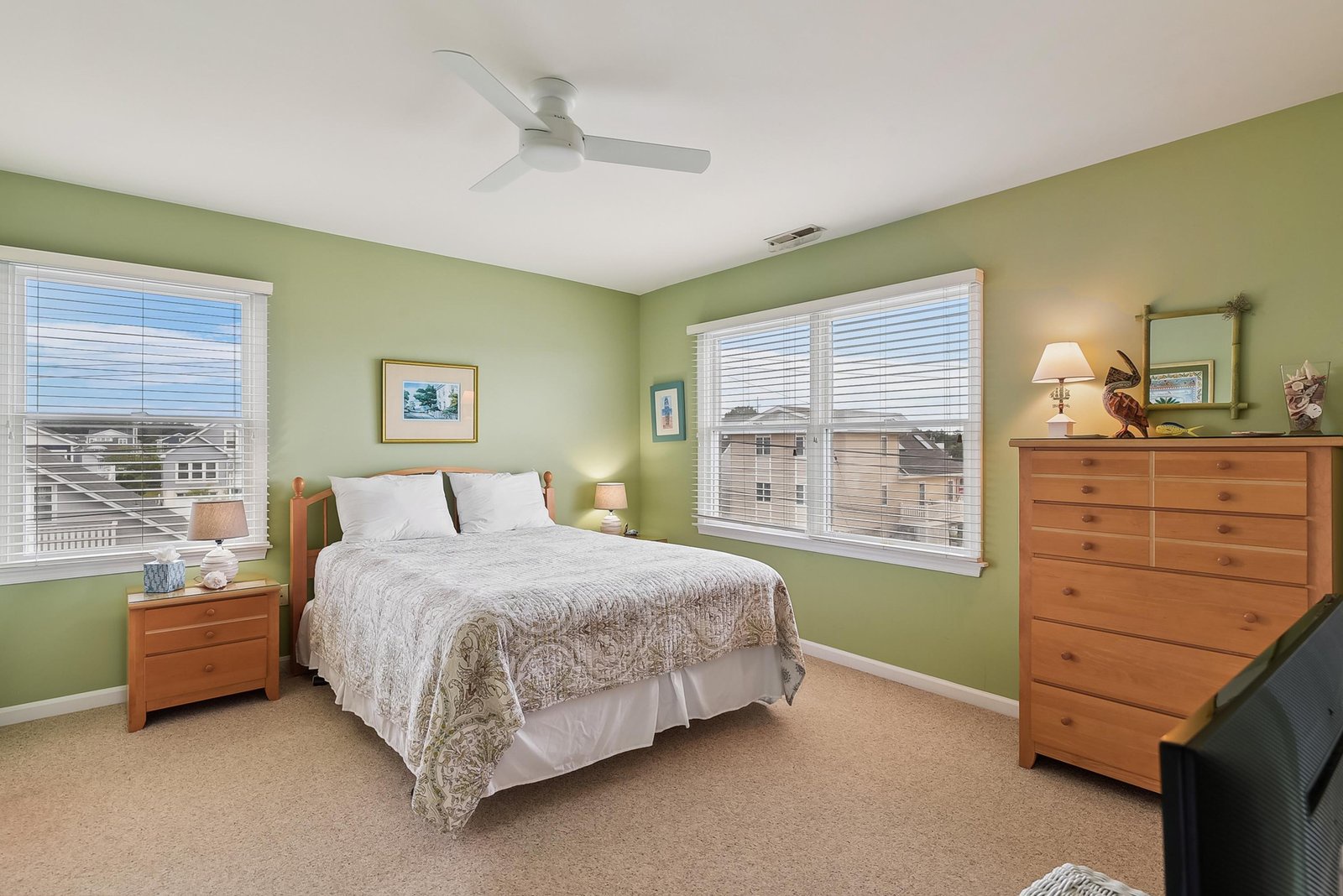 Your peaceful bedroom retreat features calming green walls, a plush bed with crisp linens, and abundant natural light streaming through large windows—perfect for waking up refreshed.