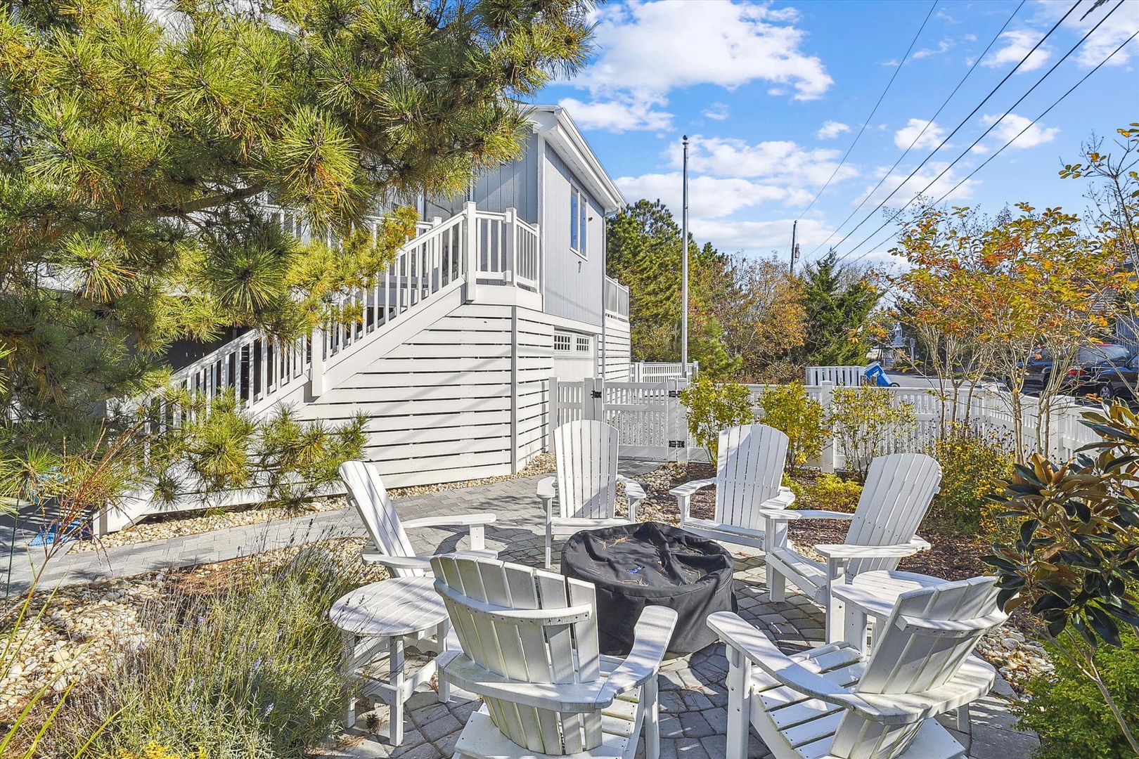A charming coastal home set amid peaceful natural surroundings, with bright Adirondack chairs around a fire pit ready for evenings spent under the stars.